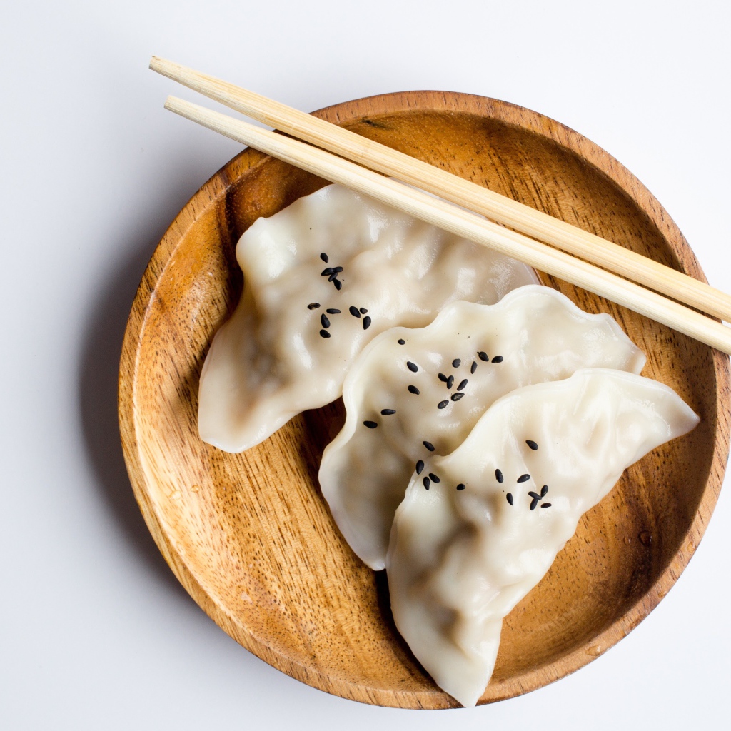 Три вареника на деревянной тарелке с палочками