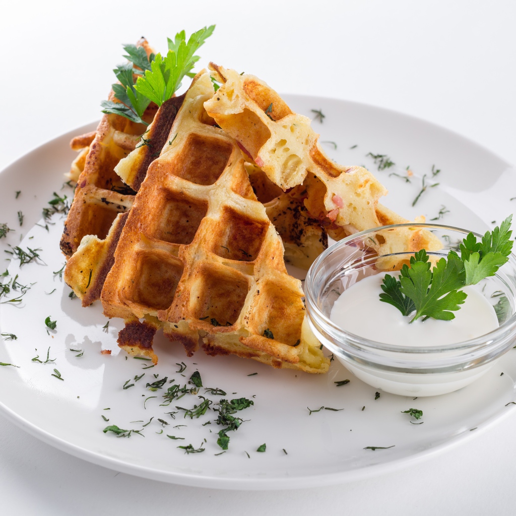Несладкие вафли на белой тарелке с зеленью и соусом