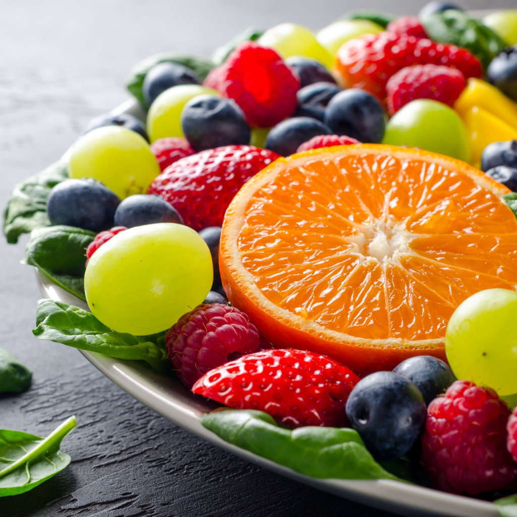 Аппетитные ягоды на тарелке с зелеными листьями базилика