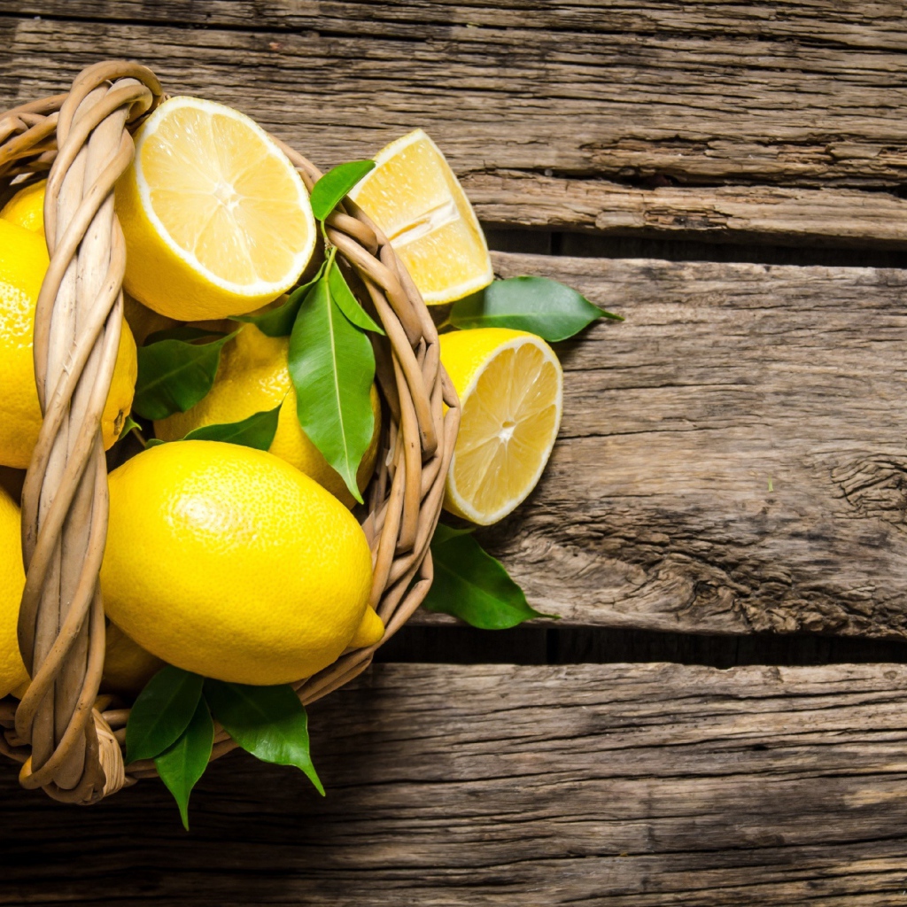 Красивые желтые лимоны в корзине на деревянном столе