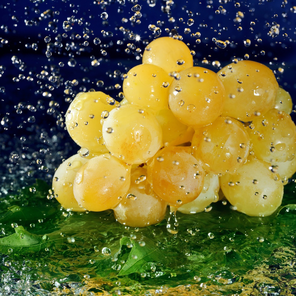Гроздь белого винограда в брызгах воды