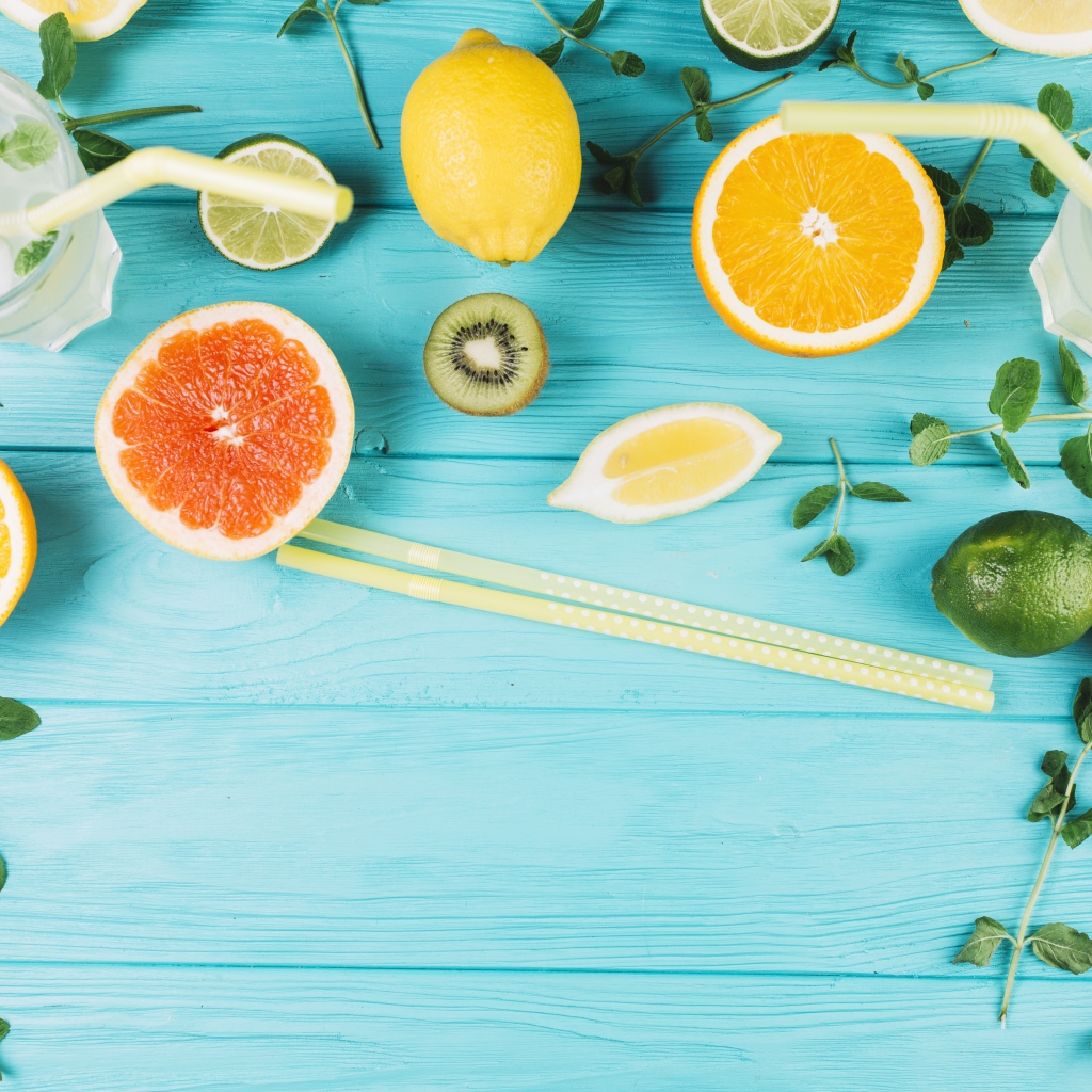 Цитрусовые фрукты на голубом столе с мятой и лимонадом