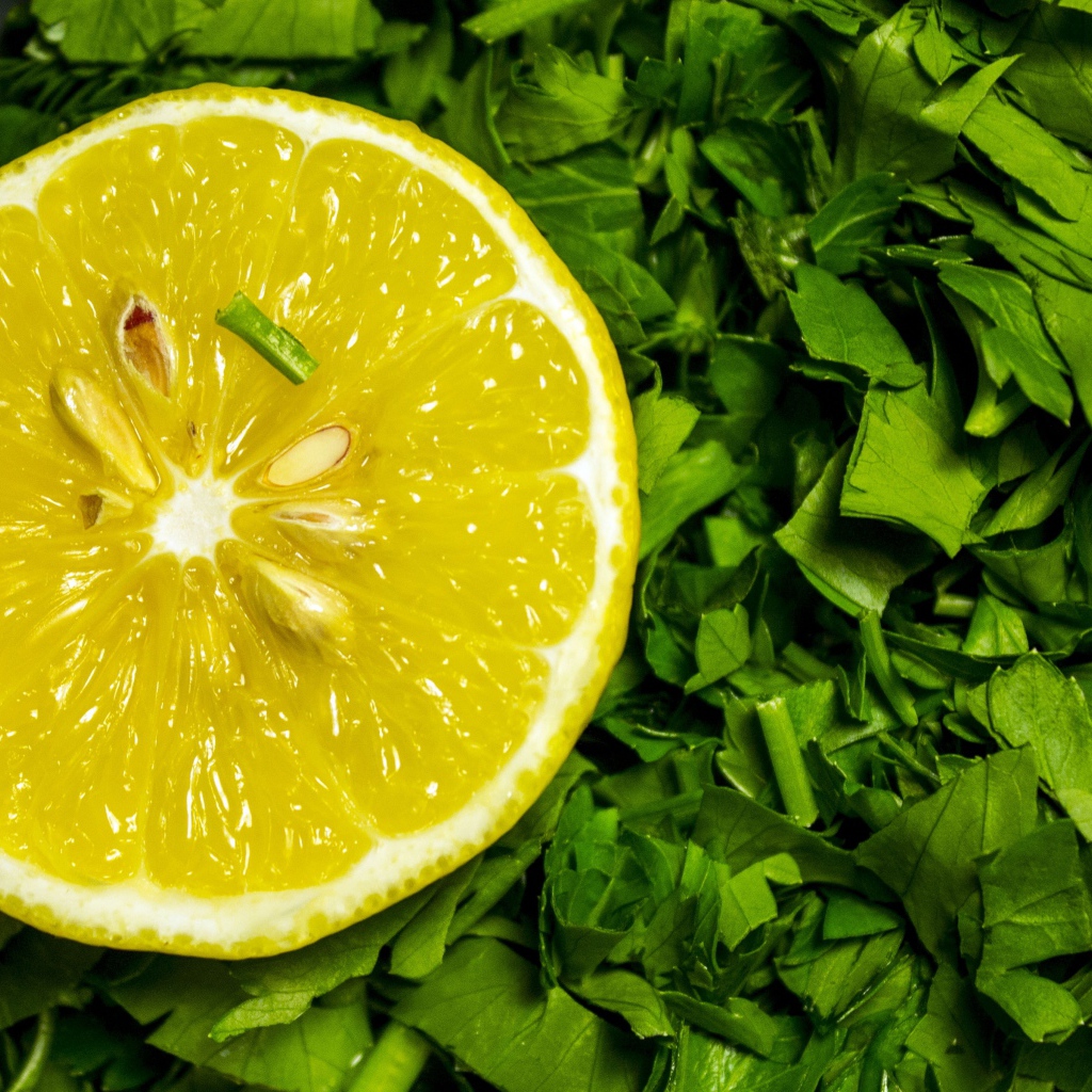 Половина желтого лимона с нарезанной зеленью петрушки 