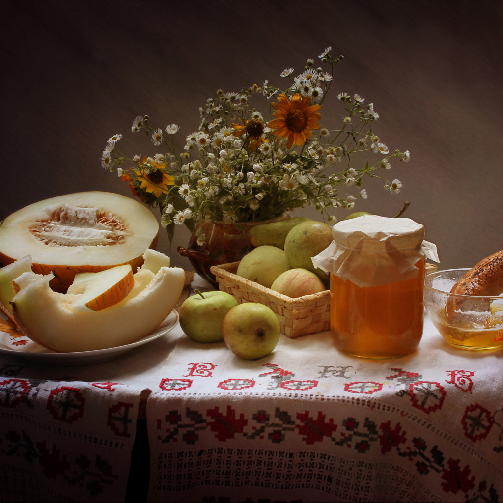 Сочная дыня с яблоками на столе с медом и букетом цветов