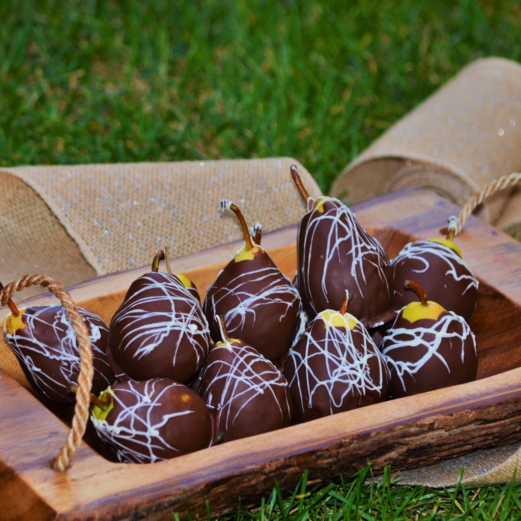 Груши в шоколадной глазури стоят на зеленой траве