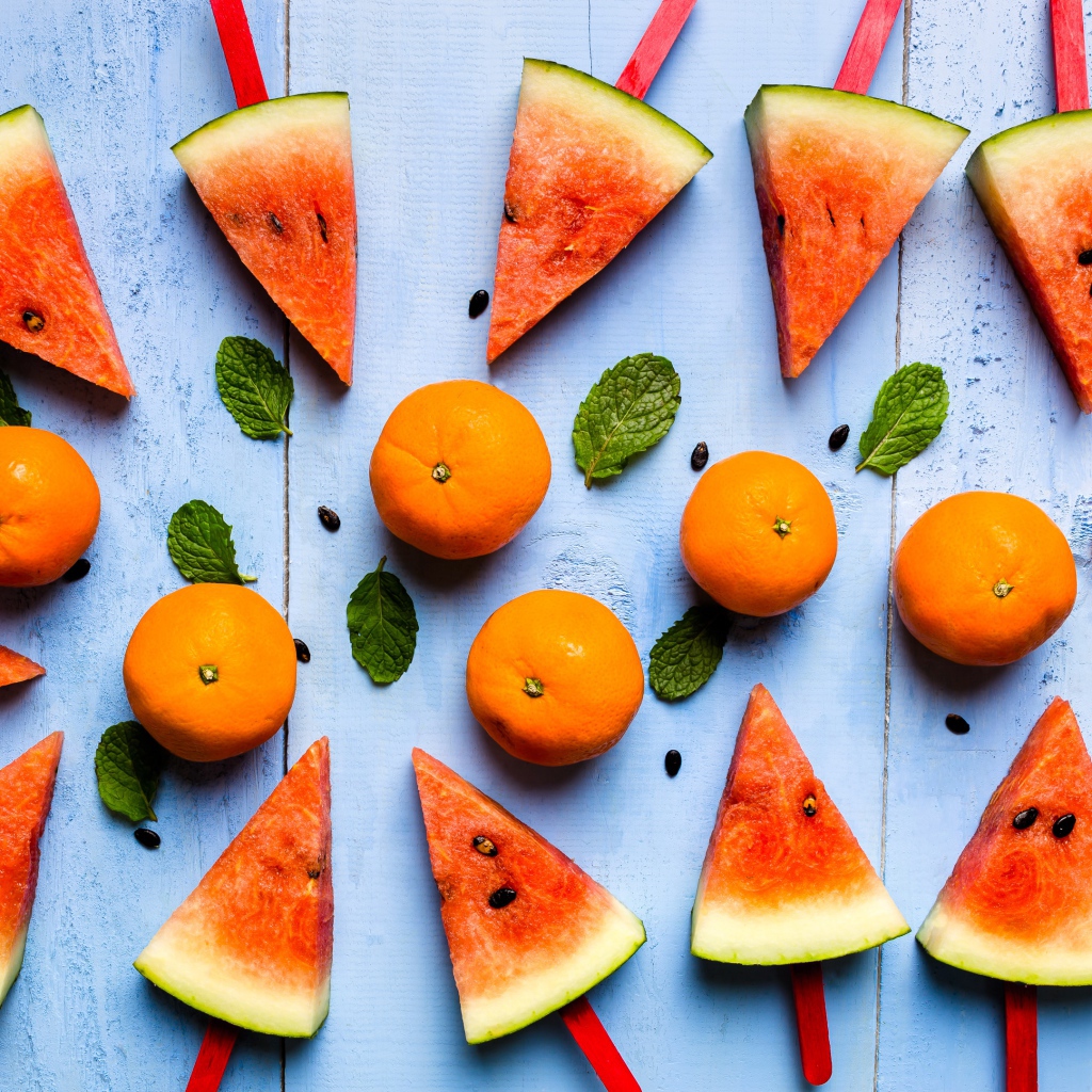 Кусочки арбуза на палочках на столе с мандаринами