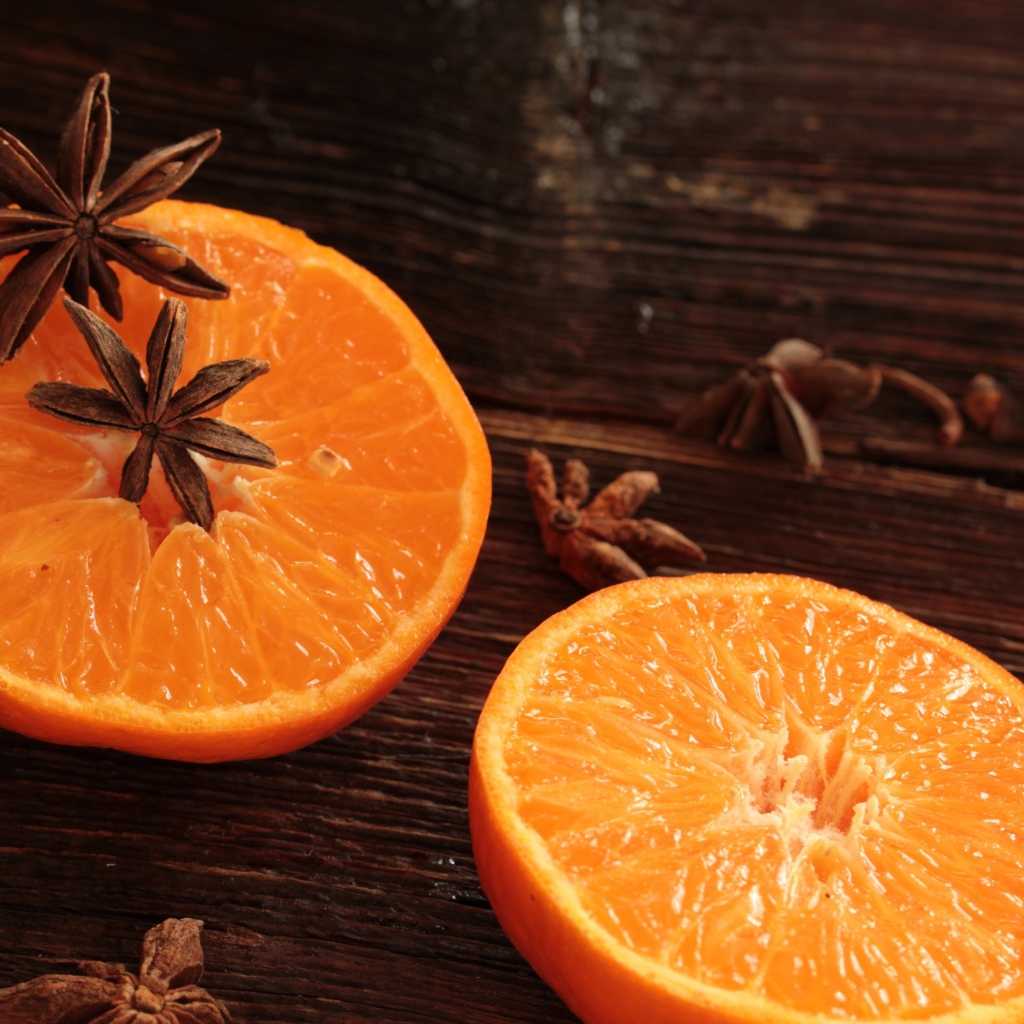 Две половины апельсина на деревянном столе с бадьяном