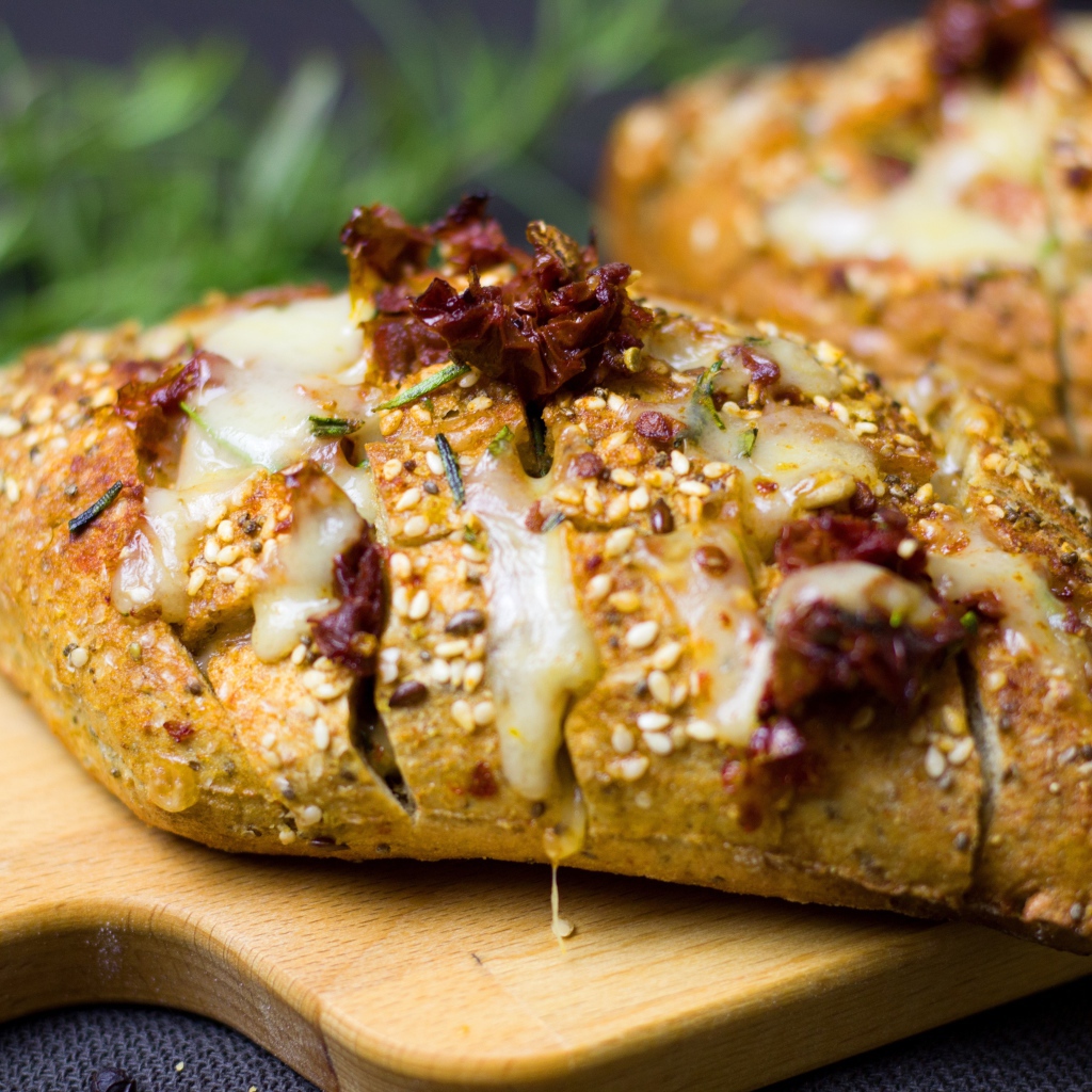 Булочка с кунжутом и сыром на разделочной доске 