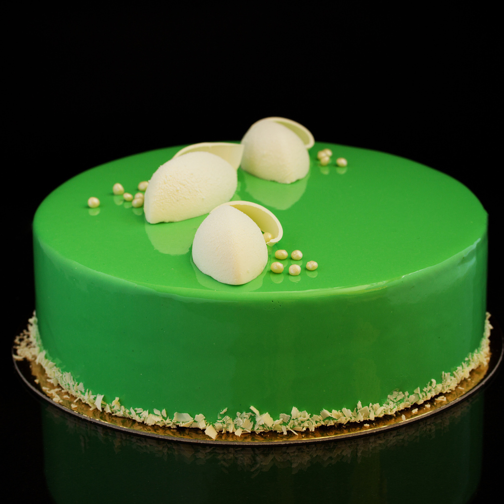 Зеленый глянцевый торт отражается в черной поверхности 