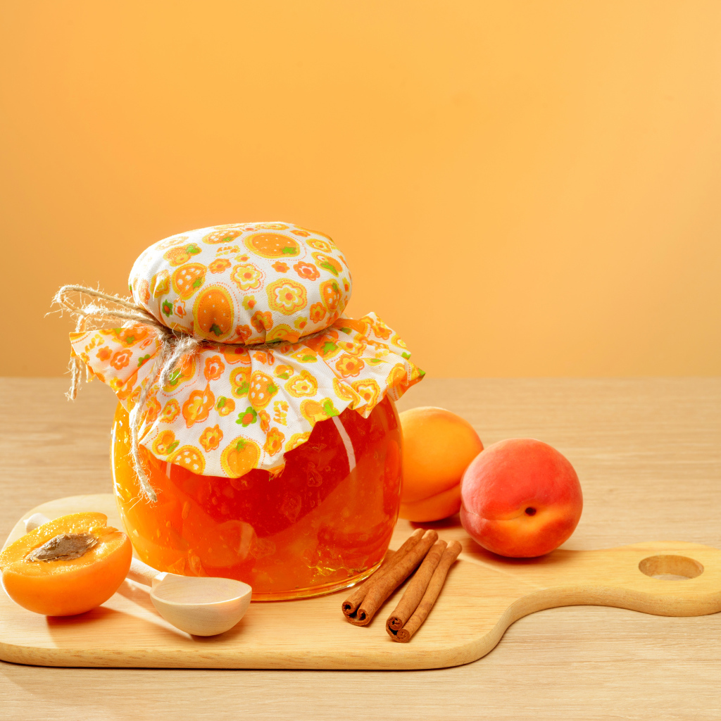 Банка абрикосового джема на столе с фруктами