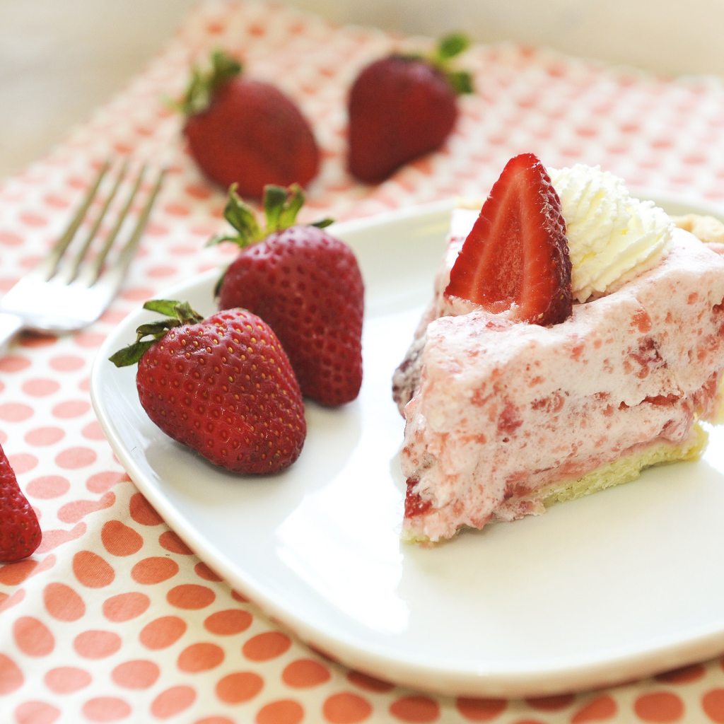 Кусок торта на тарелке со свежей клубникой 