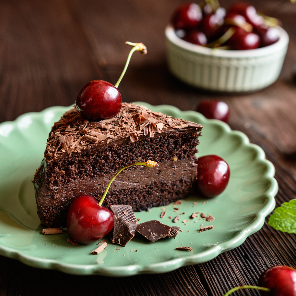 Кусок пирожного с черешнями на тарелке