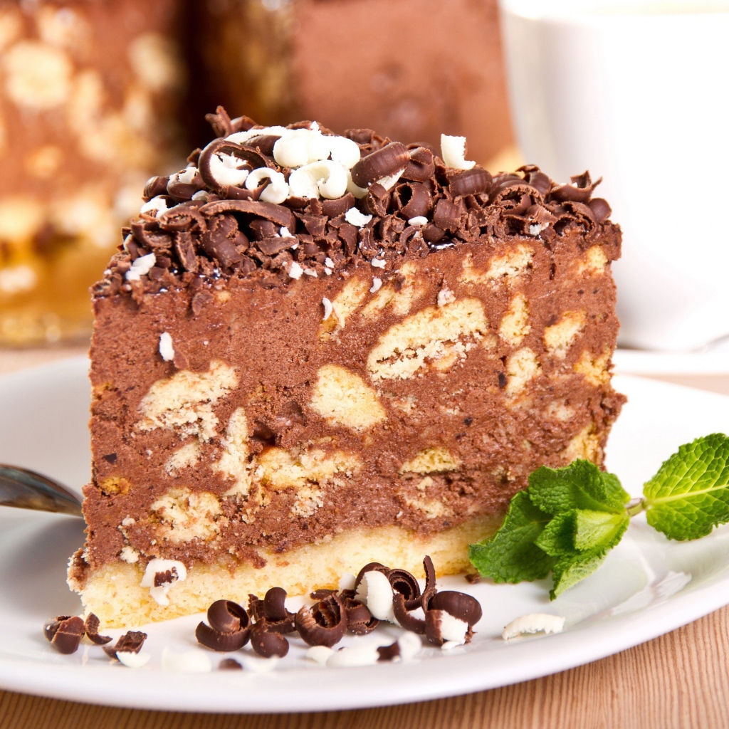 Кусок торта с шоколадом и листьями мяты на тарелке
