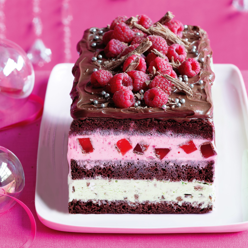 Кусок пирога с шоколадом и малиной на розовом фоне