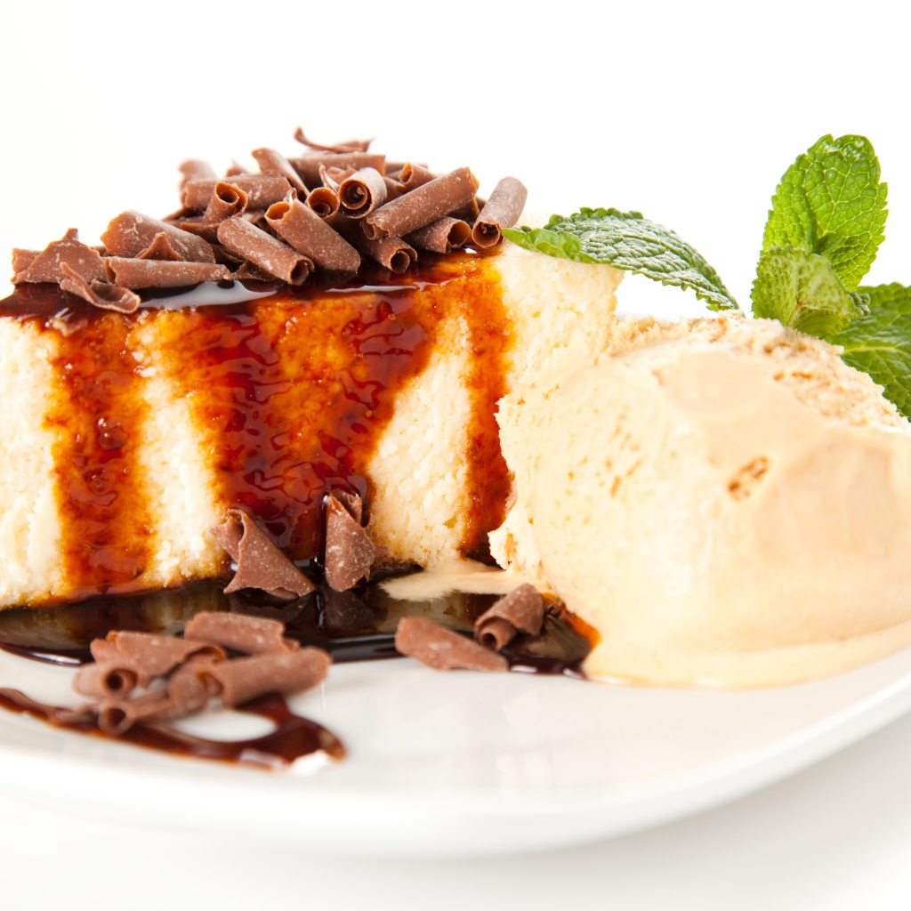 Кусок чизкейка с шоколадом и шариком мороженого на белой тарелке 