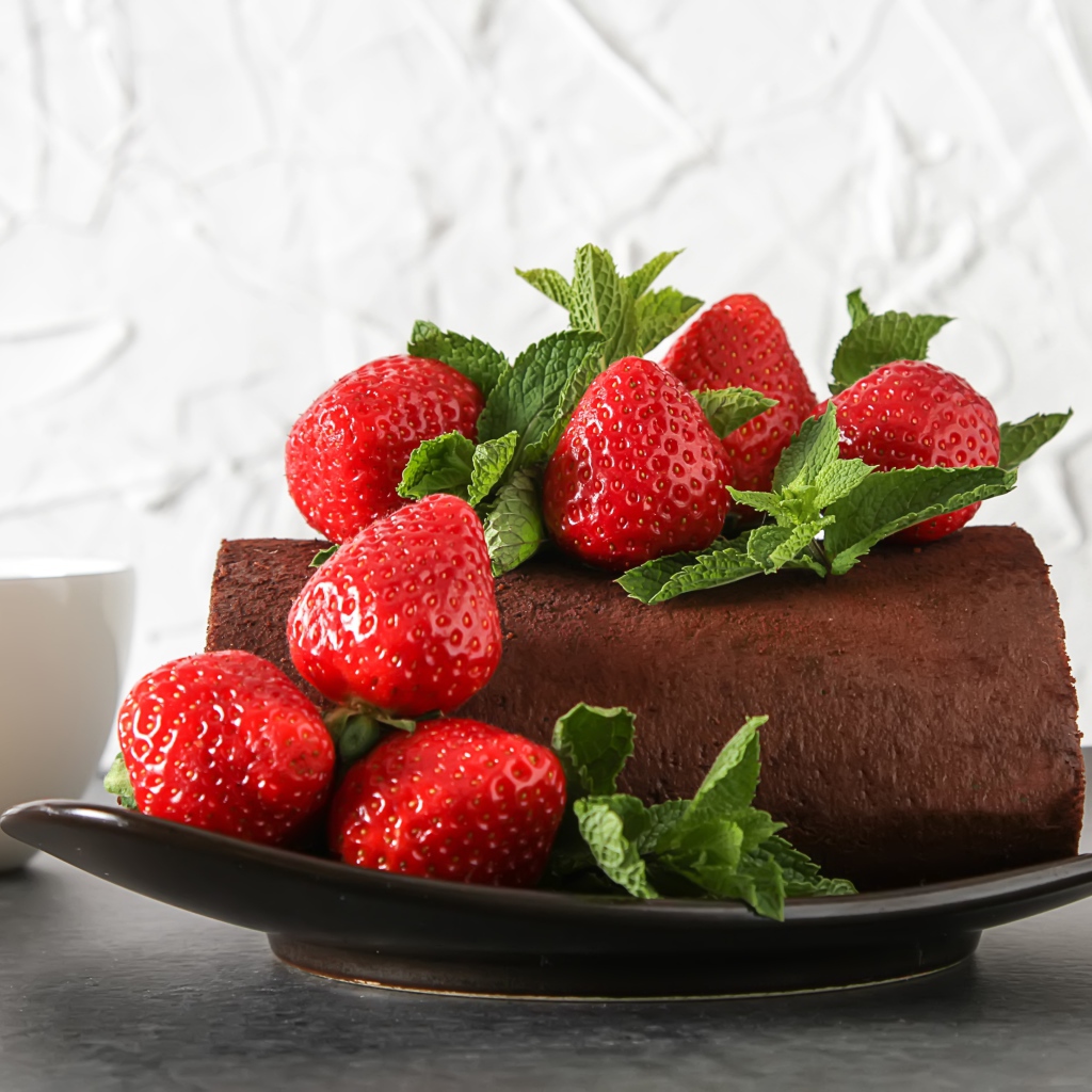 Кусок шоколадного торта со свежей клубникой на тарелке