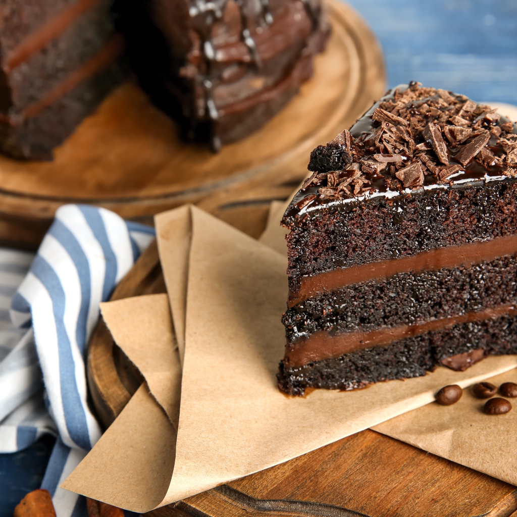 Кусок вкусного шоколадного торта на столе с кофейными зернами