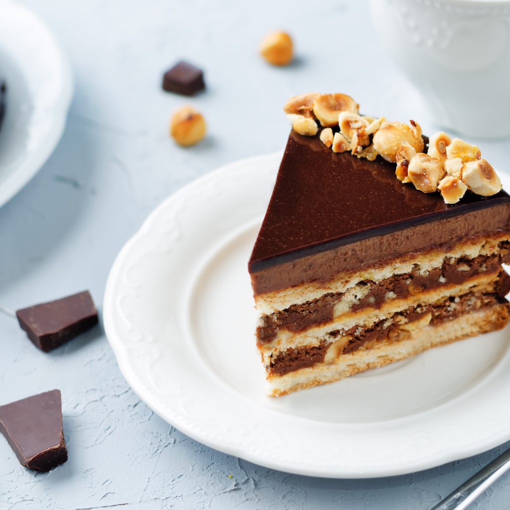 Кусок аппетитного торта с орехами на белой тарелке