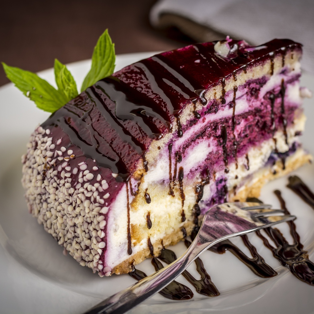 Кусок черничного пирога с джемом на белой тарелке с вилкой