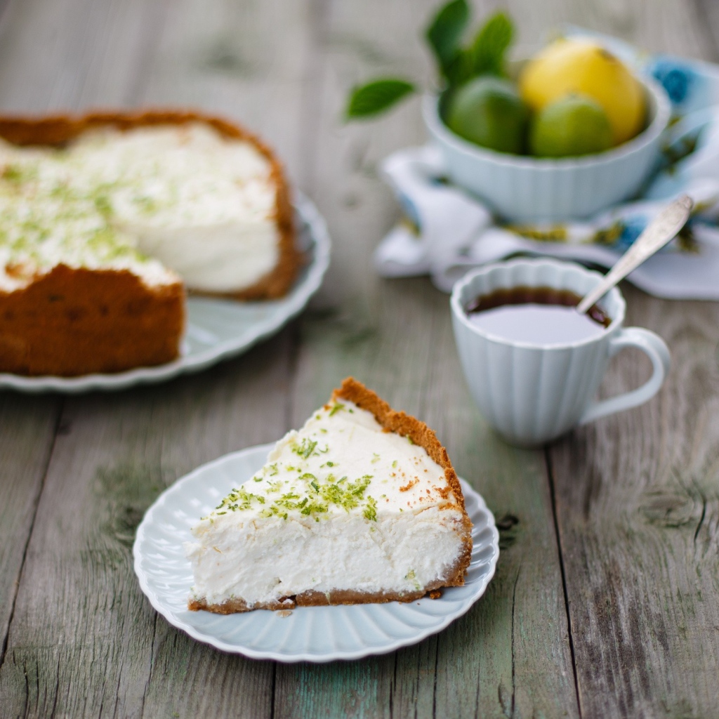 Кусок чизкейка на столе с чашкой чая