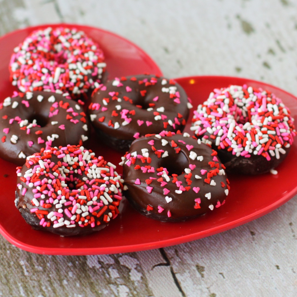 Аппетитные пончики на красной тарелке в форме сердца