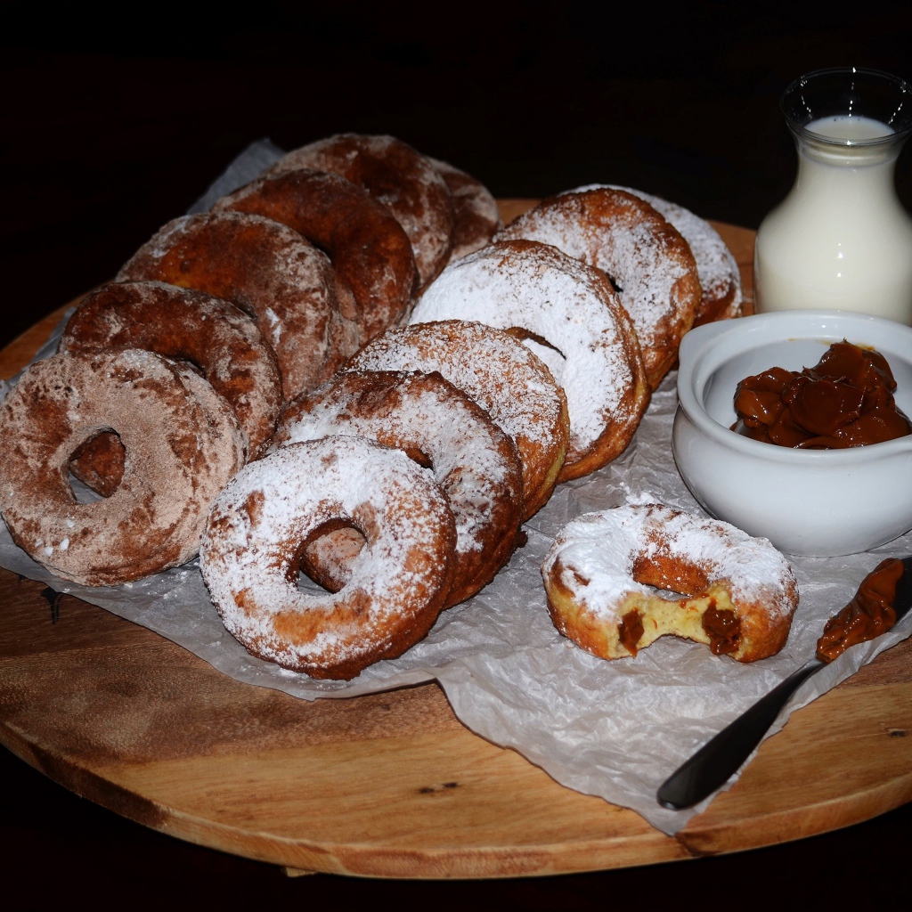 Аппетитные пончики со сгущенкой и свежим молоком на столе