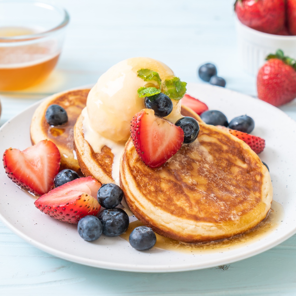 Аппетитные оладьи с мороженым, медом и ягодами клубники и черники