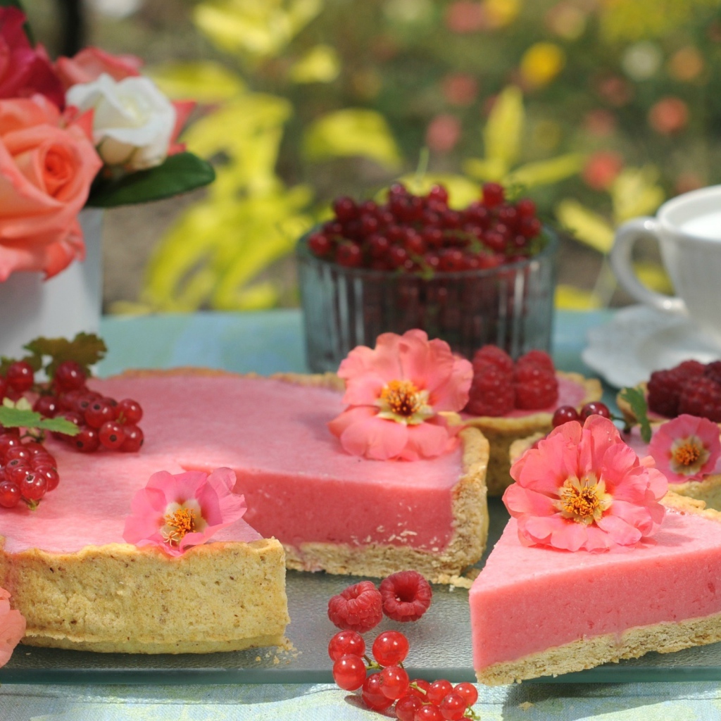 Аппетитный пирог с ягодами малины и красной смородины на столе с цветами