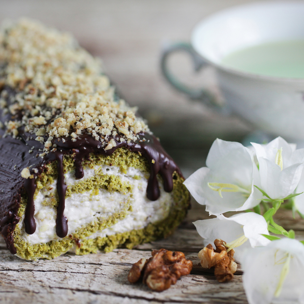 Аппетитный сладкий рулет с шоколадом на столе с белыми цветами колокольчика