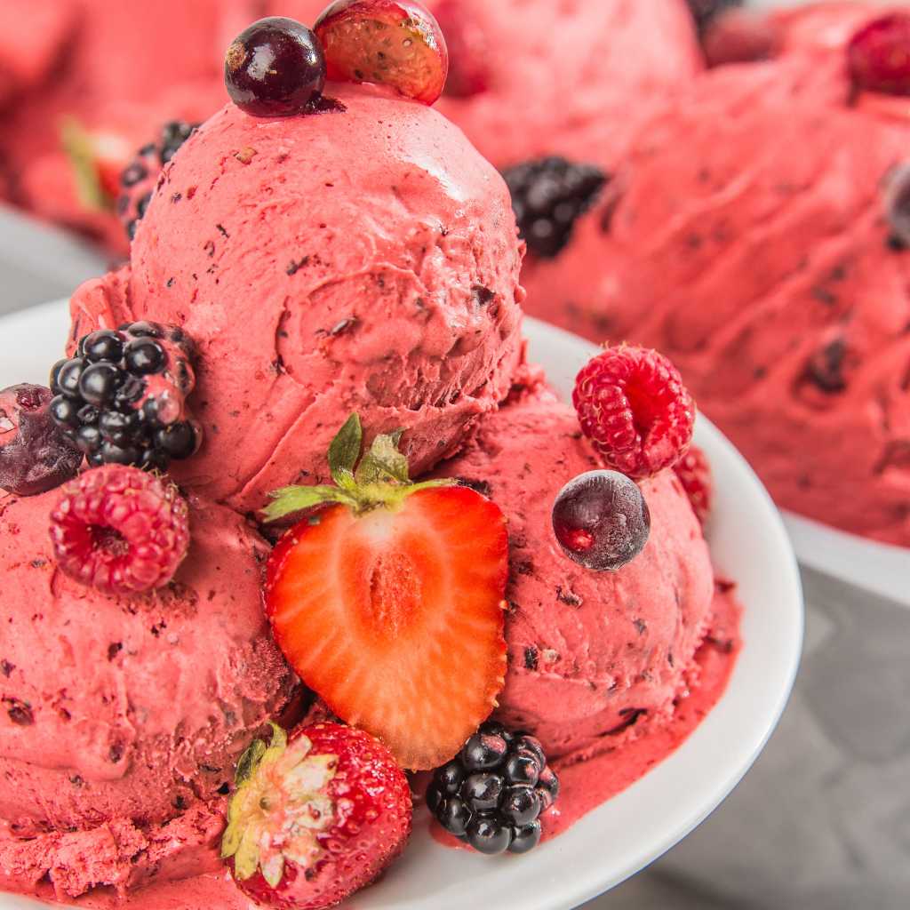 Шарики мороженого с ягодами на белой тарелке