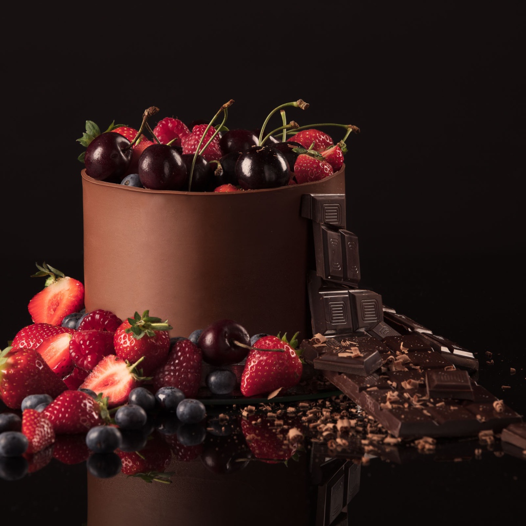 Черный шоколад с ягодами черники, малины, клубники и вишни на черном фоне