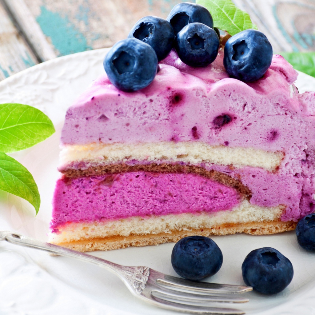 Торт с черничным муссом и свежими ягодами черники на белой тарелке 