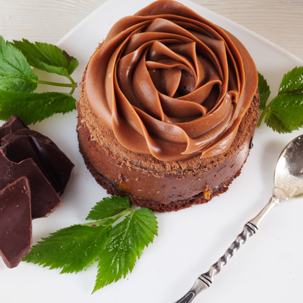 Пирожное с шоколадной кремовой розой на тарелке