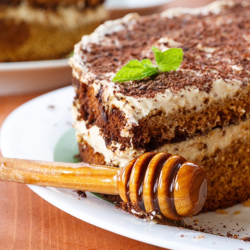 Торт с кремом и шоколадом на тарелке с ложкой для меда