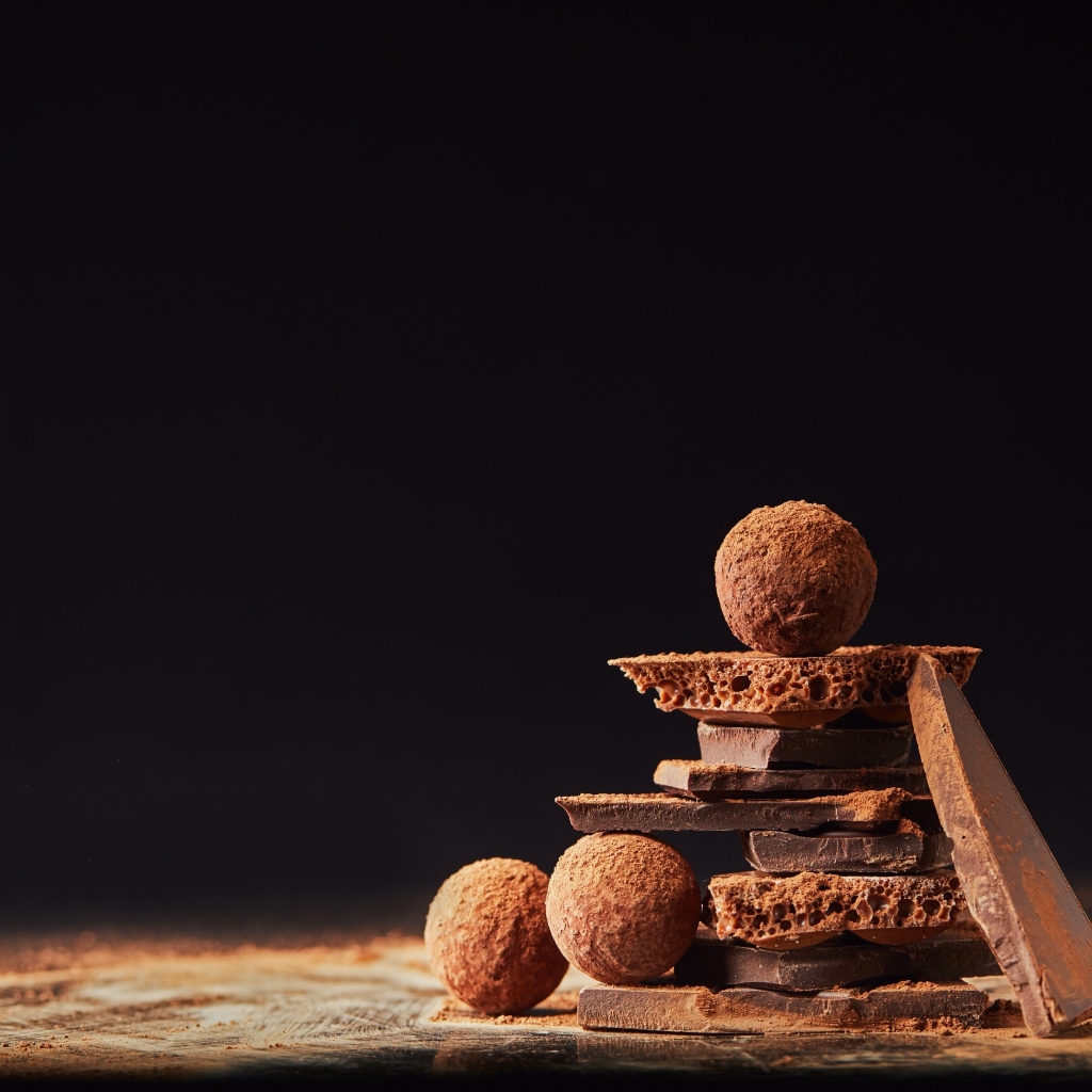 Шоколадные шарики и кусочки шоколада на черном фоне