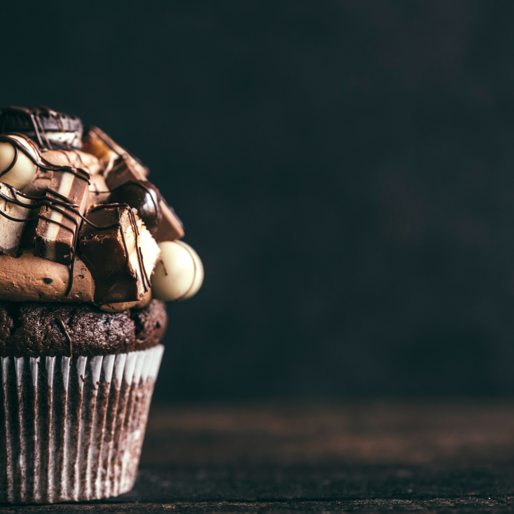 Шоколадный кекс с кремом и конфетами на сером фоне