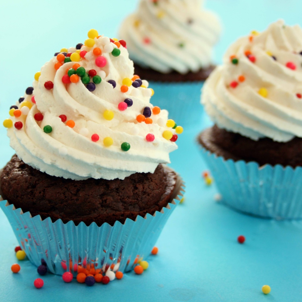 Шоколадные кексы со сливками и цветными брызгами на голубом фоне