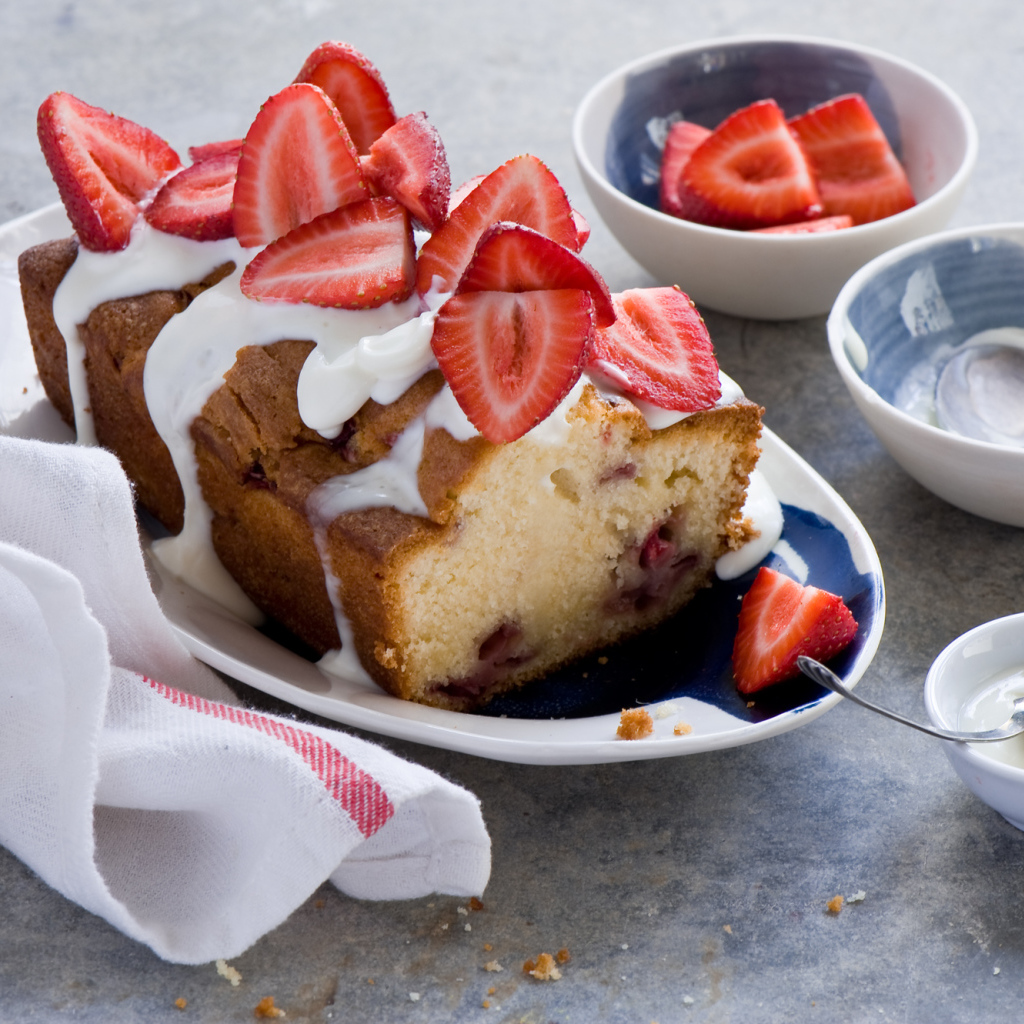 Кекс с кремом на тарелке со свежей клубникой 