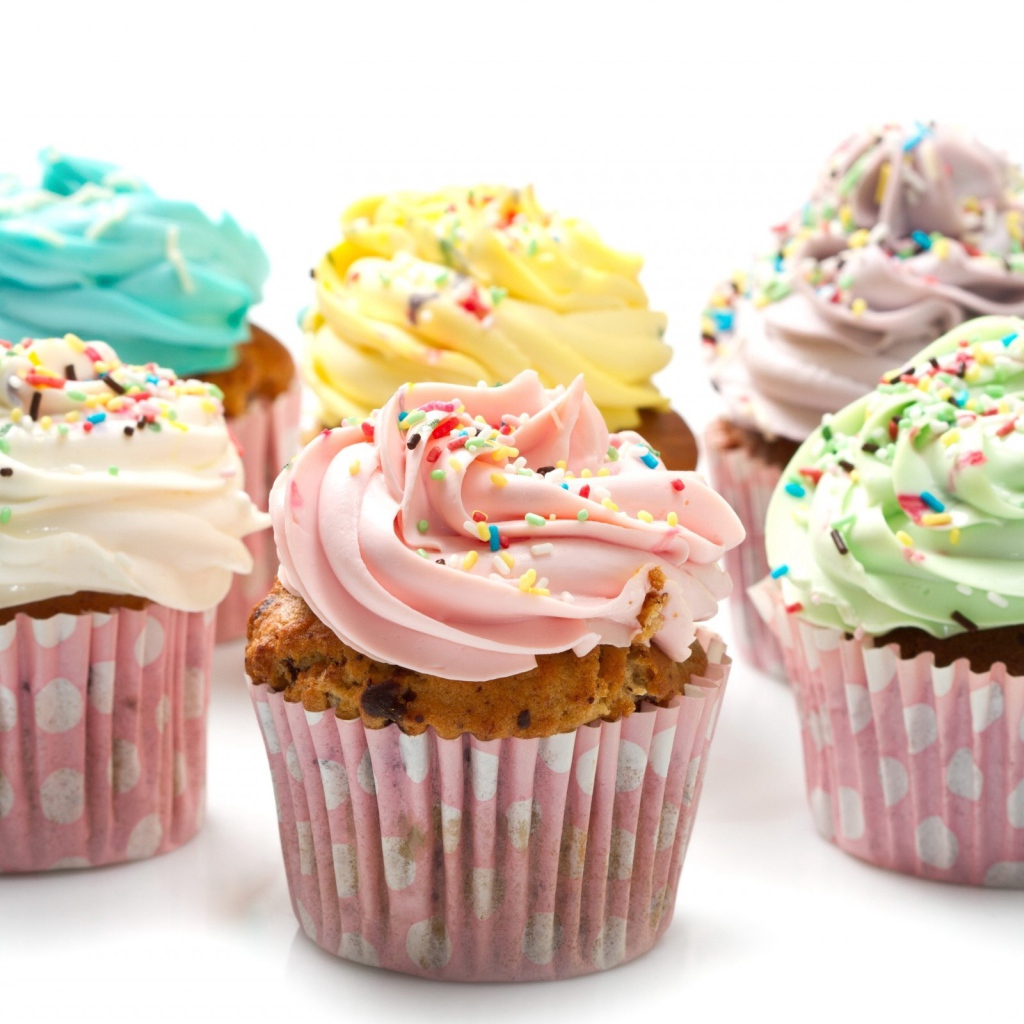 Кексы с разноцветным кремом на белом фоне