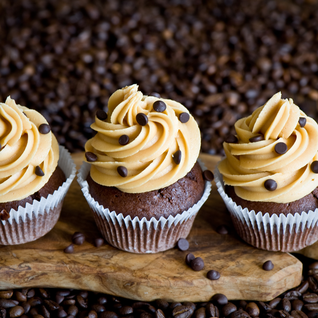 Кексы с кремом и зернами кофе на столе 