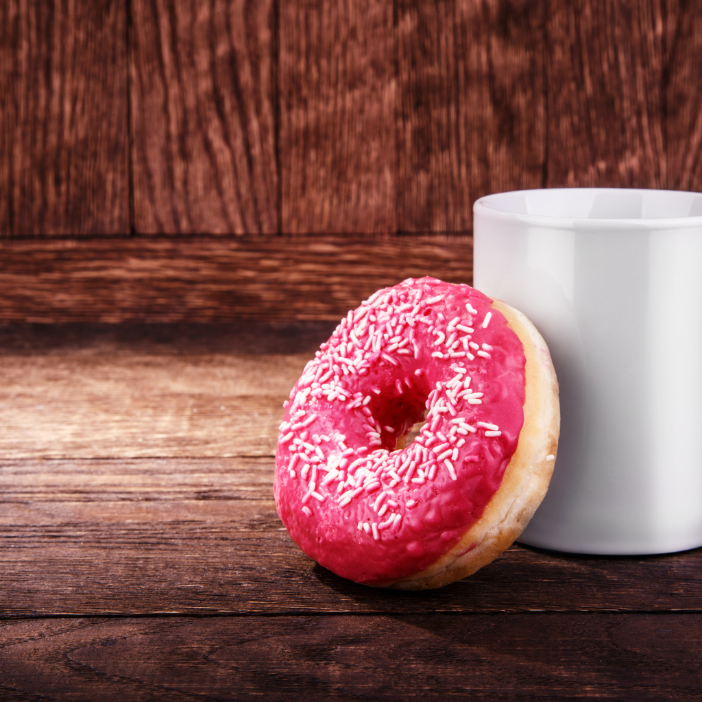 Пончик с белой кружкой на деревянном столе