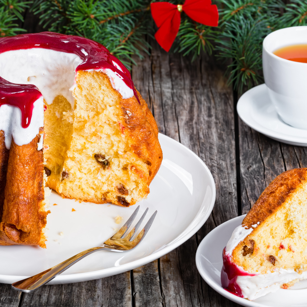 Праздничный кекс с глазурью на столе с чашкой чая