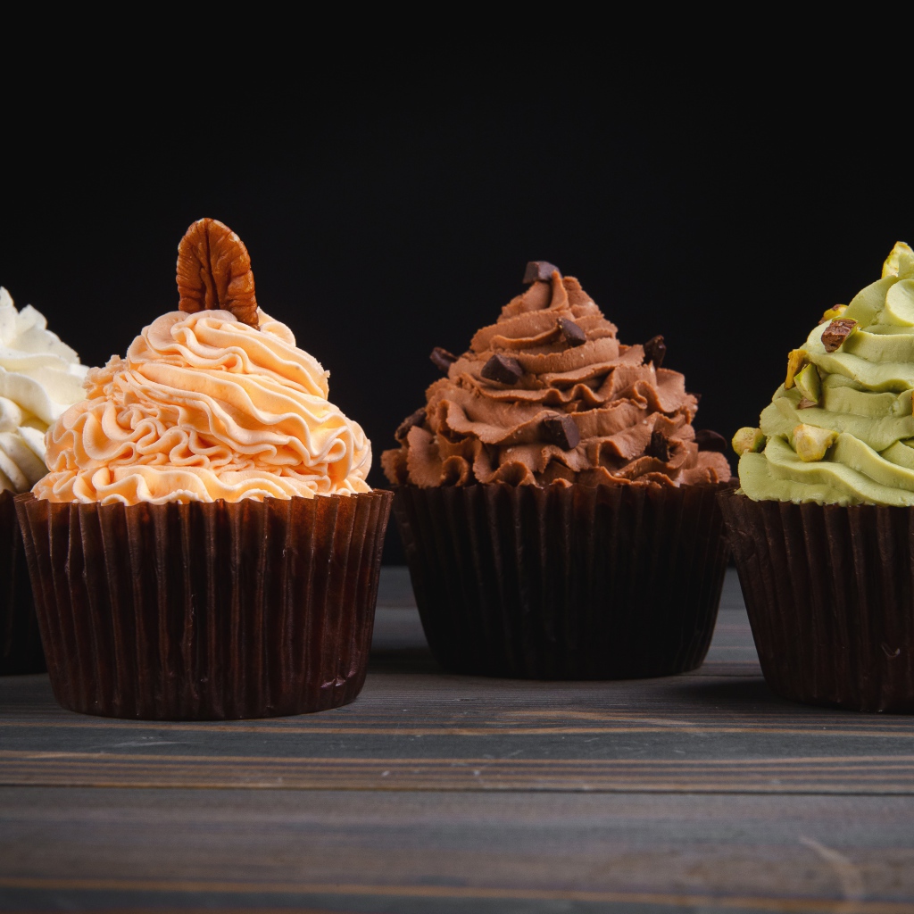 Четыре аппетитных капкейка с кремом на черном фоне