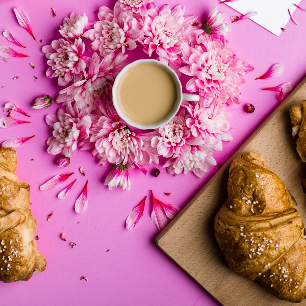 Свежие круассаны на столе с чашкой какао и цветами хризантемы