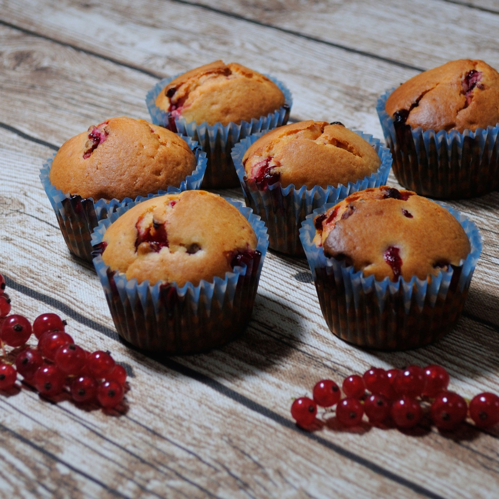 Fresh cupcakes with red currants on a wooden table