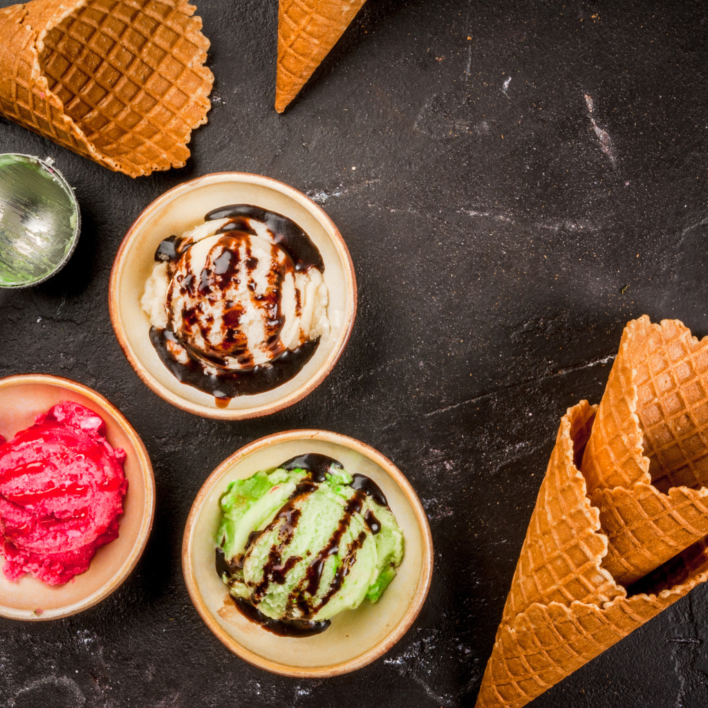 Шарики мороженого с вафельными рожками на столе 