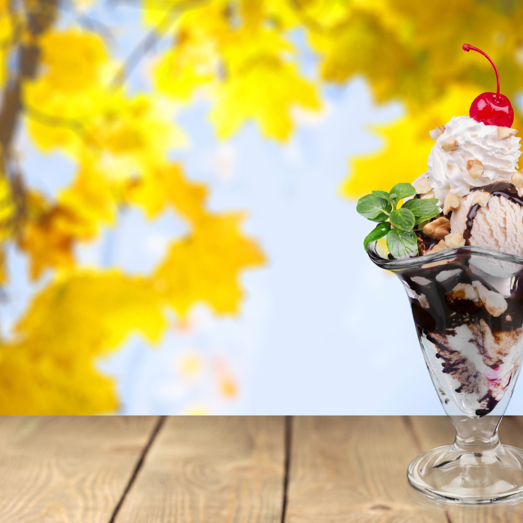 Мороженое в креманке с вишенкой на фоне желтых листьев