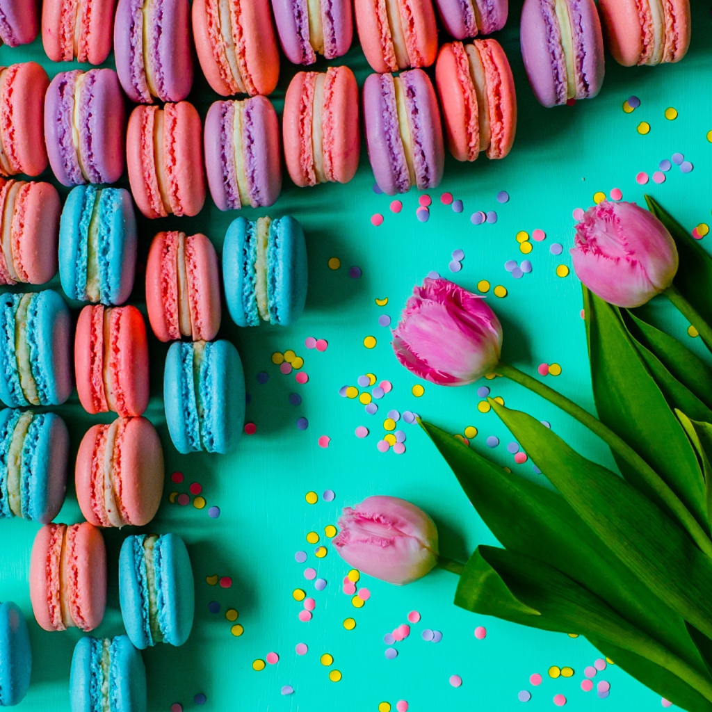 Разноцветные десерты макарун на столе с тюльпанами