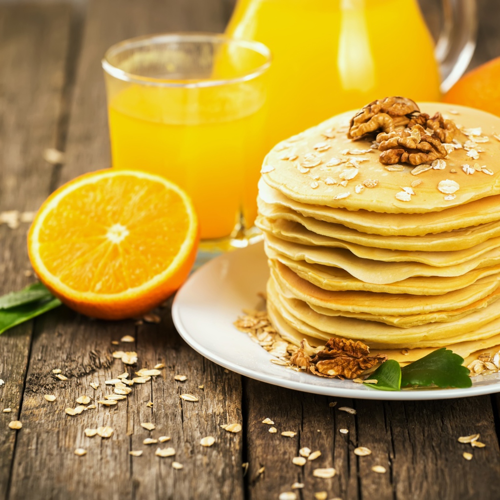 Оладьи с орехами на столе с апельсиновым соком и апельсинами