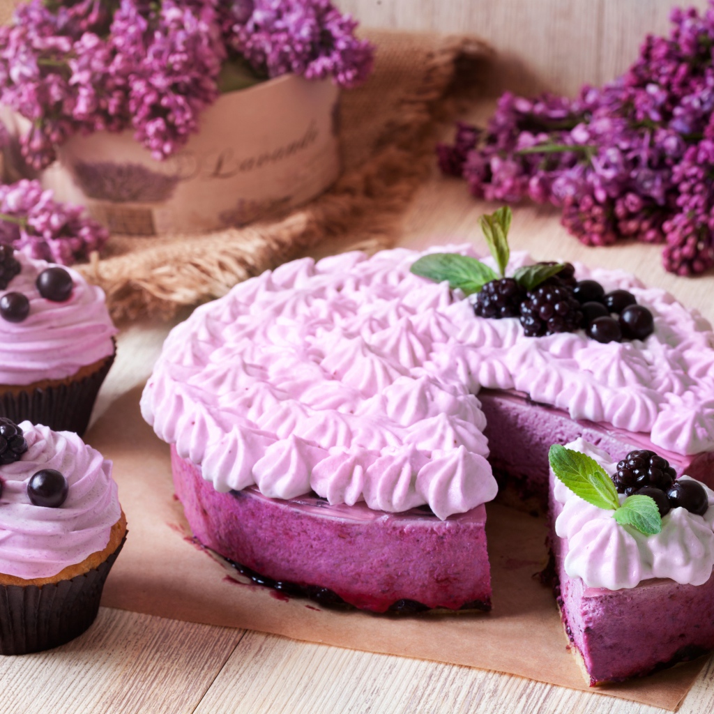 Пирог с кремом и вкусными кексами с черникой на столе с цветами сирени